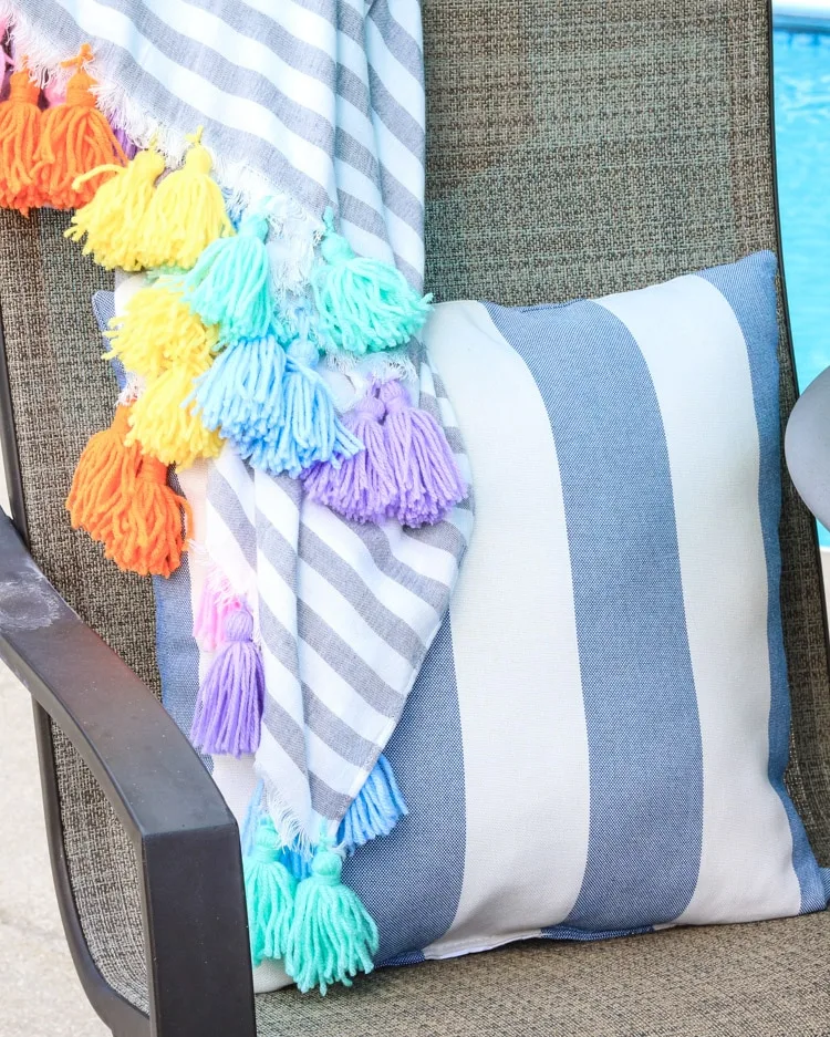 A Hawaiian themed decor idea including a bright colorful tassel blanket and a striped blue pillow.