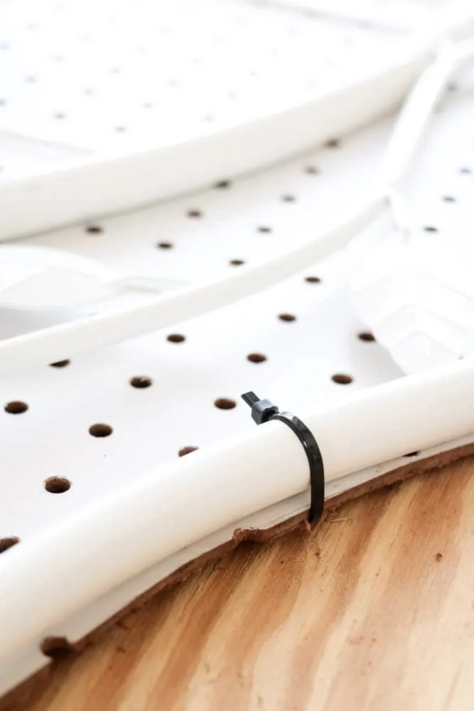 Upholstered headboards DIY by attaching a pegboard to a metal headboard with zip ties.