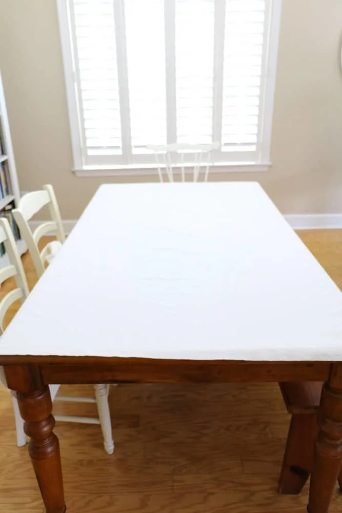 Lay the ironed drop cloth material on a table to make an upholstered headboard