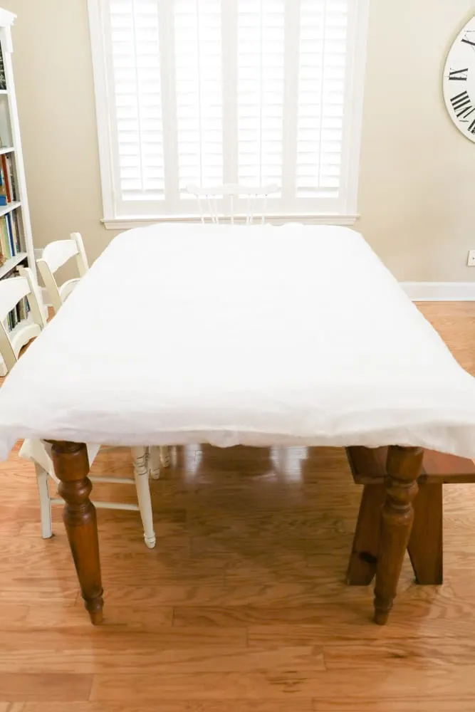Lay the ironed drop cloth material on a table then quilt batting to make an upholstered headboard