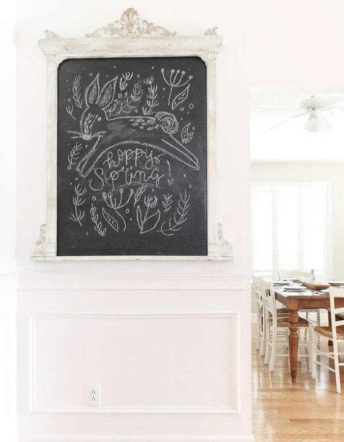 DIY chalkboard that says 'hoppy Spring' written in cursive below a leaping bunny. Around the text and bunny, greenery is drawn in the chalk.