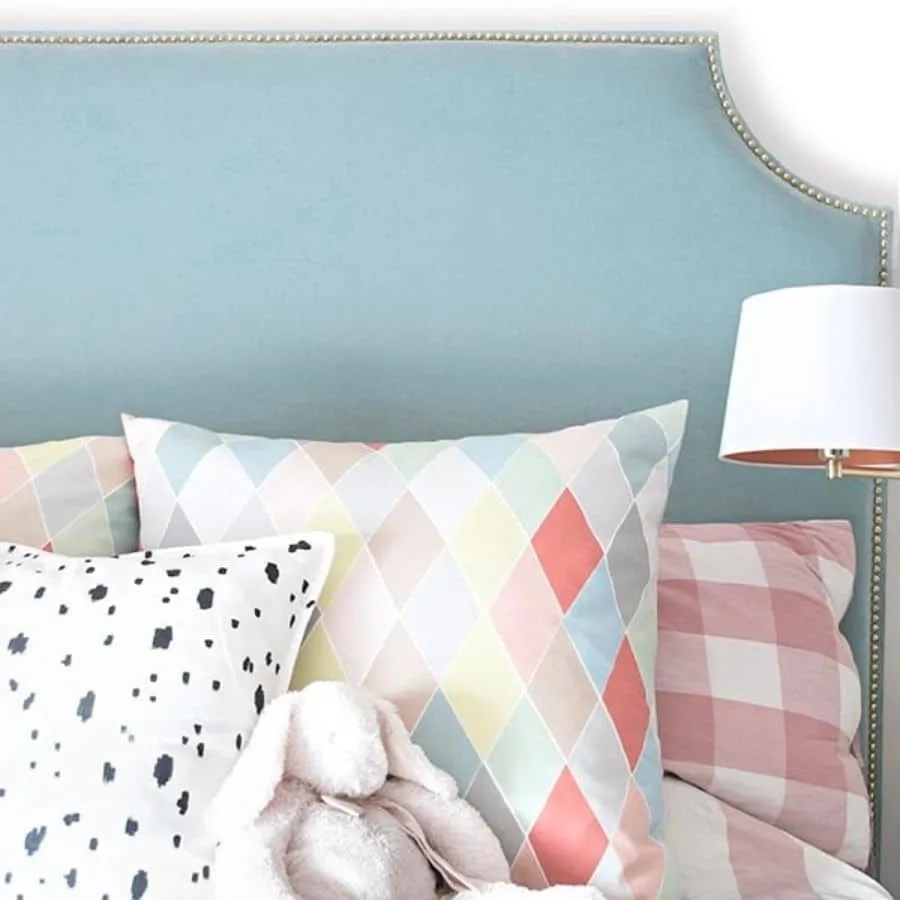 A DIY upholstered headboard with a studded nail trim.