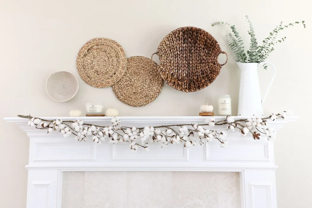 Baskets, candles, and cotton garland on a fall mantle.