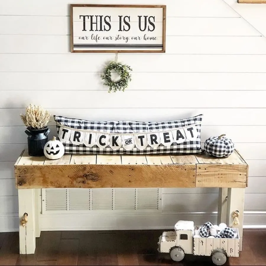 A wooden bench decorated with a bolster pillow and halloween decor.