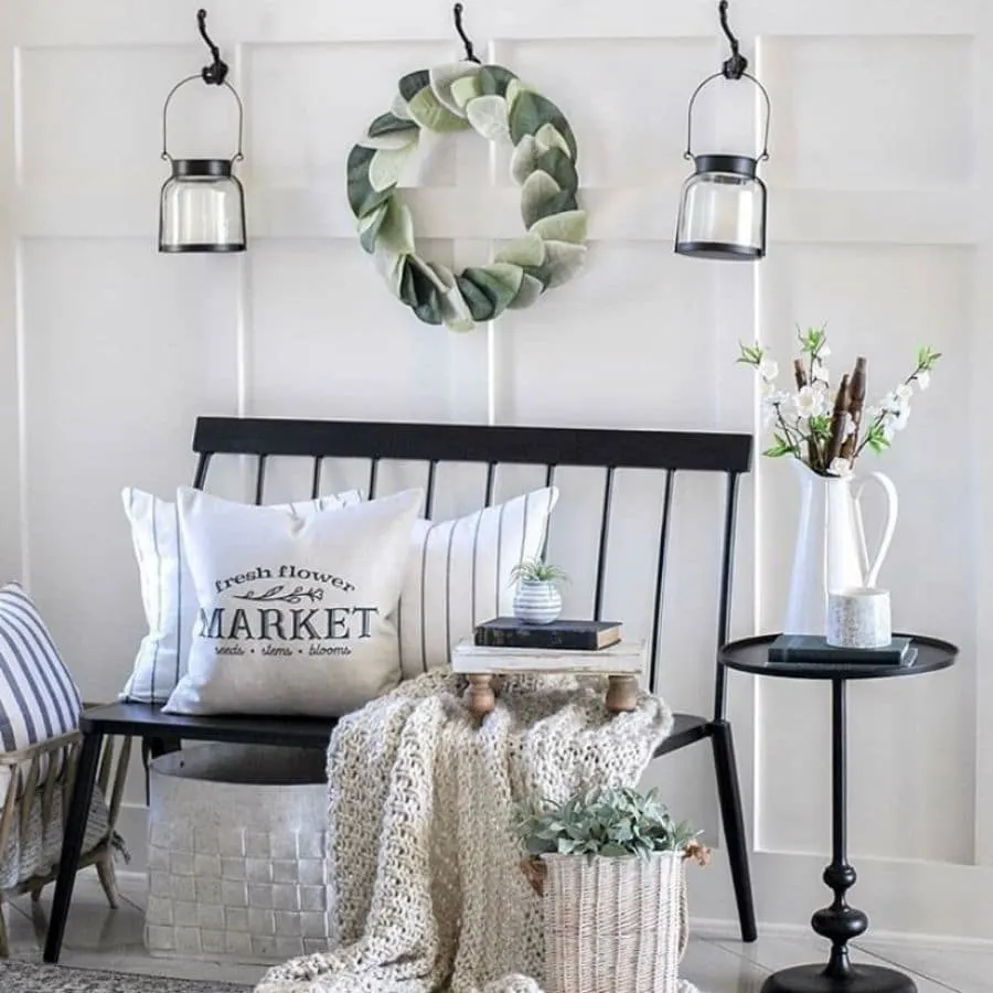 A black bench styled with a chunky throw blanket and books ad pillows.