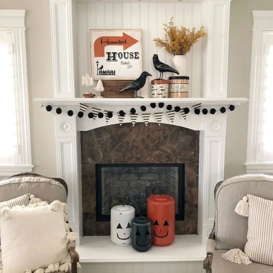 Haunted House sign, ravens, jack o lanterns, black and white garland and banner on a white fireplace mantle.