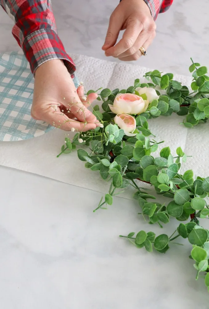 Adding babies breath under peonies on DIY Dollar Tree wreath