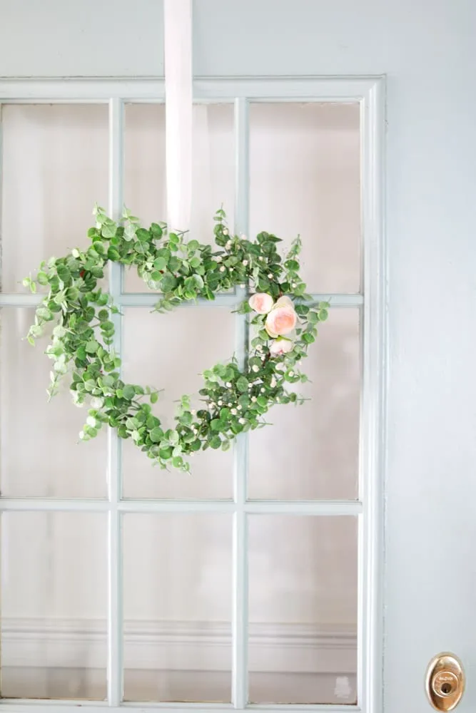 Dollar Tree DIY heart shaped floral wreath hanging on a front door