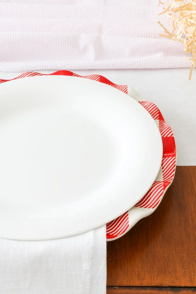 Valentine table setting with red and white buffalo check dinner plate and white plate stacked