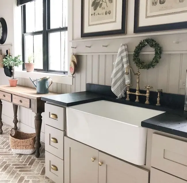 A laundry or mudroom painted in Anew Gray by Sherwin Williams with a large farmhouse sink