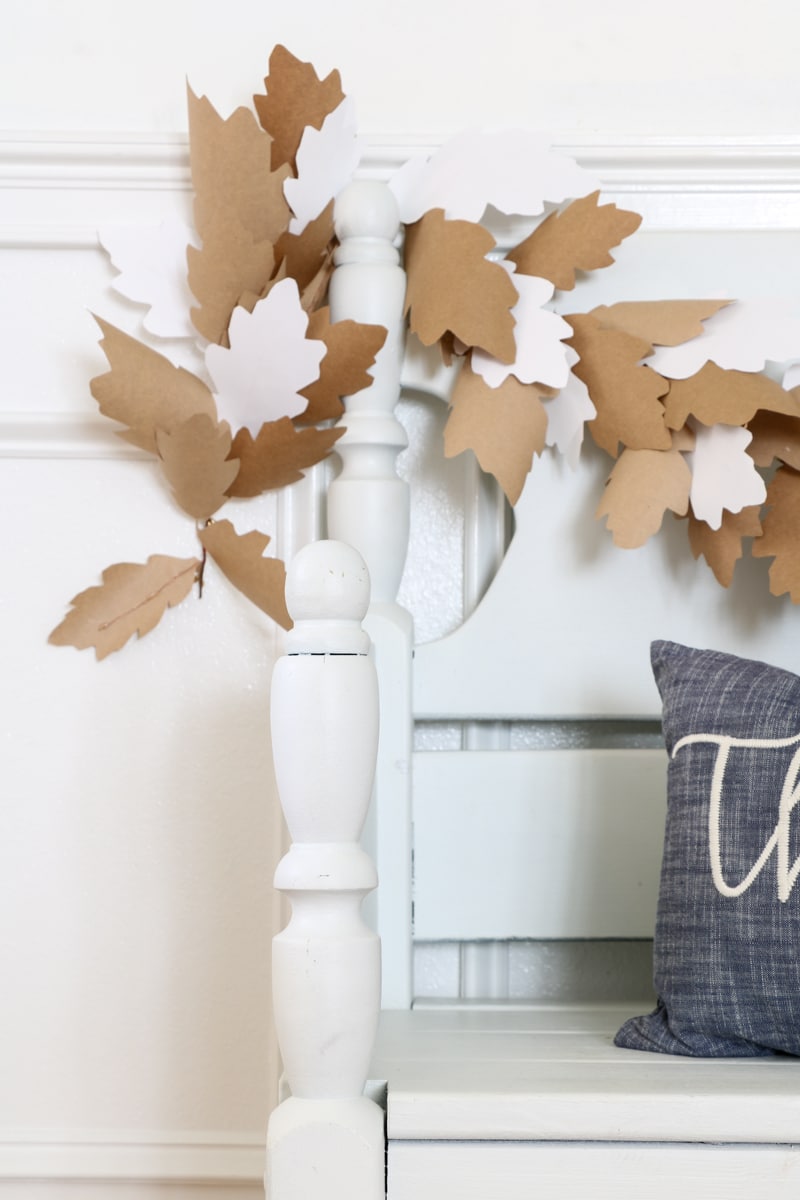 DIY paper leaf garland in brown and white paper hung on a staircase railing for fall