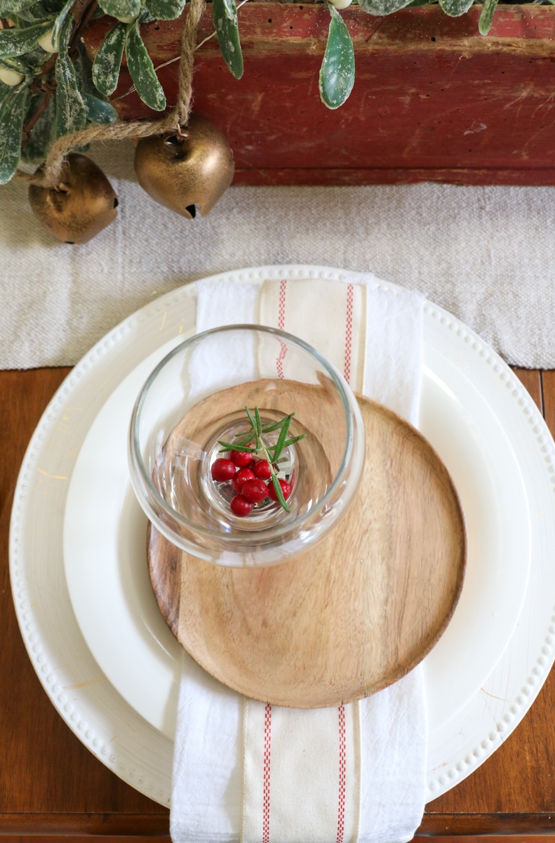 Wine glass filled with cranberries and rosemary as a place setting centerpiece