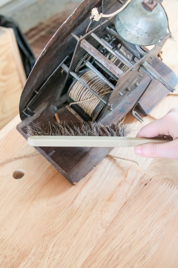 Removing dust from clock mechanism with a horse hair brush