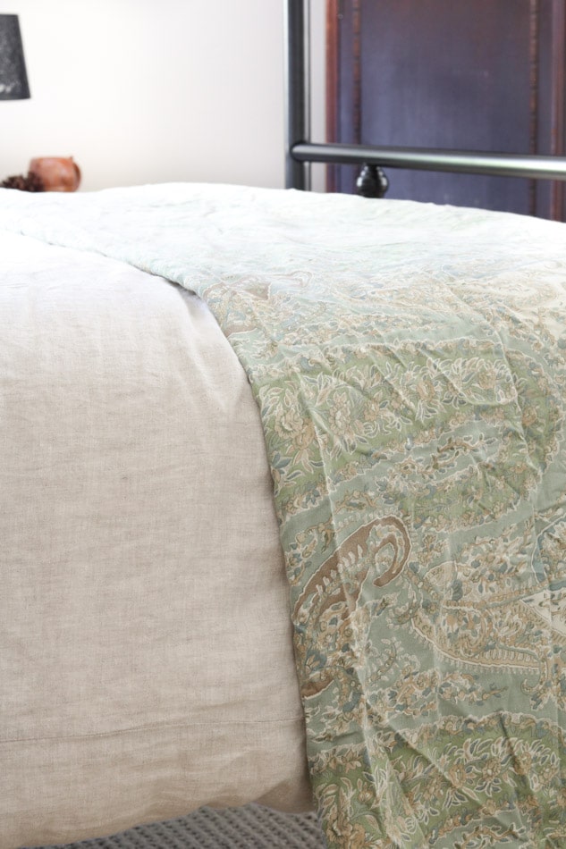Linen duvet over with paisley throw folded at the end of the a bed