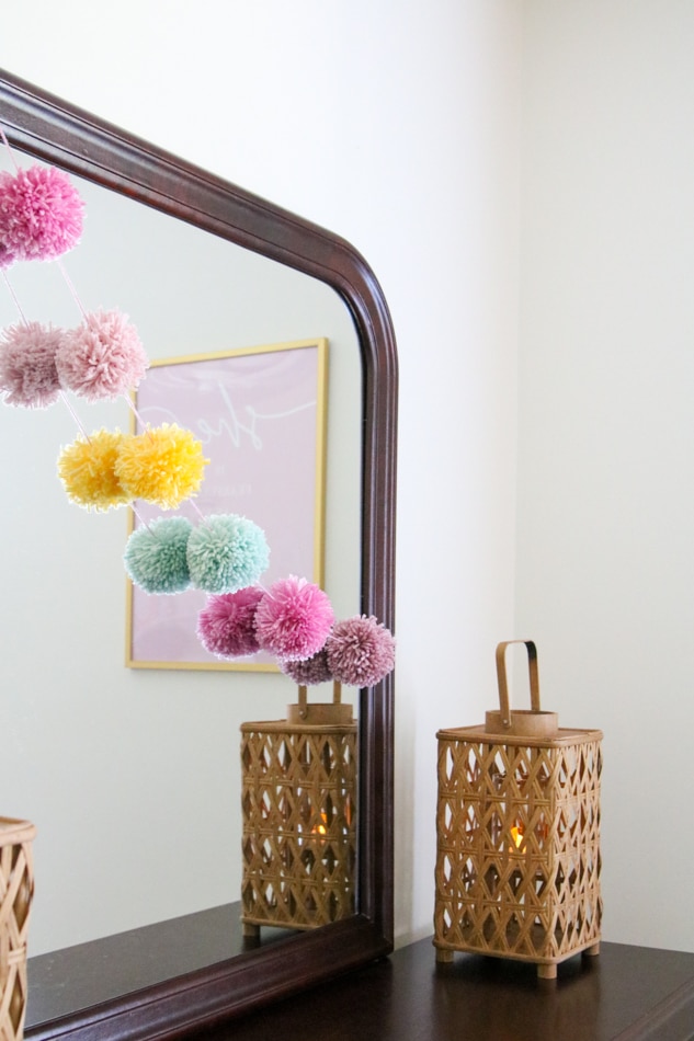 Pom pom garland hanging on a mirror in a kids room