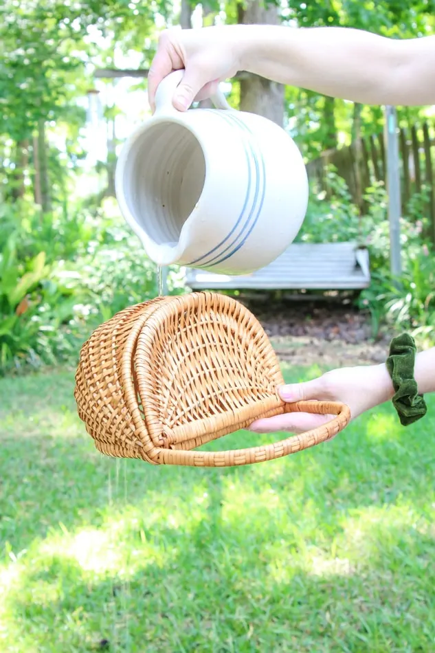 Cleaning a wicker basket by rinsing it with clear water after washing it with detergent