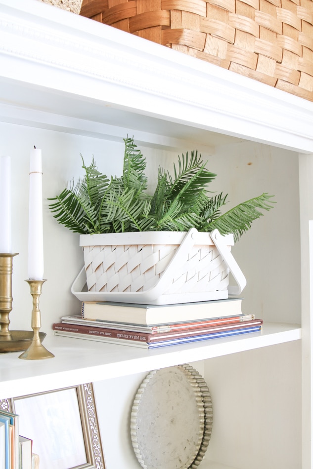 White painted basket used as decoration on a bookcase