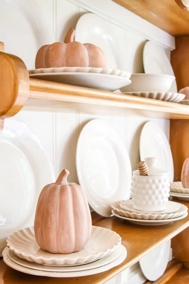 Clay colored pumpkins that are white washed on a hutch