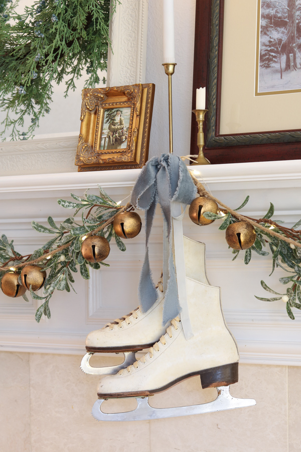 Blue Christmas decor ideas using a blue velvet ribbon and hanging vintage white ice skates on a fireplace mantel