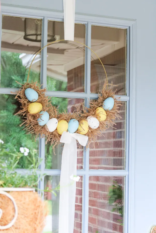Easter egg wreath hanging on a front door for spring porch decorations.