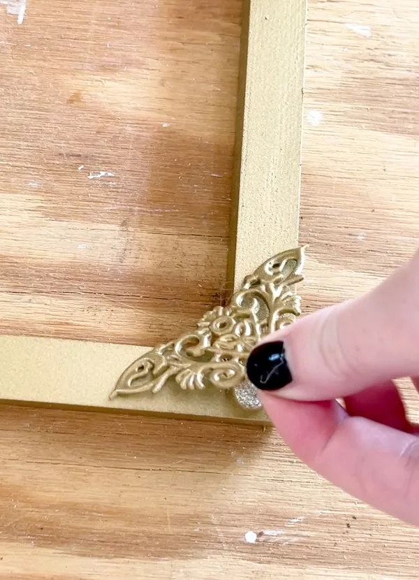 Hot glue ornate design to wood frame for canvas