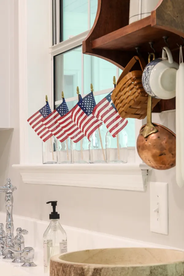Kitchen window decorated with clear jars and American stick flags