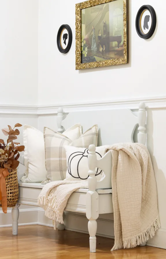 Decorating a bench for fall with pillows in neutral colors and blankets