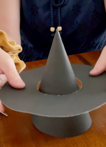 Place the brim over the cone and push down gently until the brim is snug onto the cone of the paper witch hat