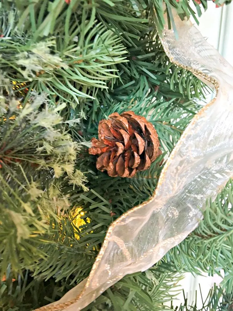 Greenery garland, ribbon and pinecone decorations for a small porch