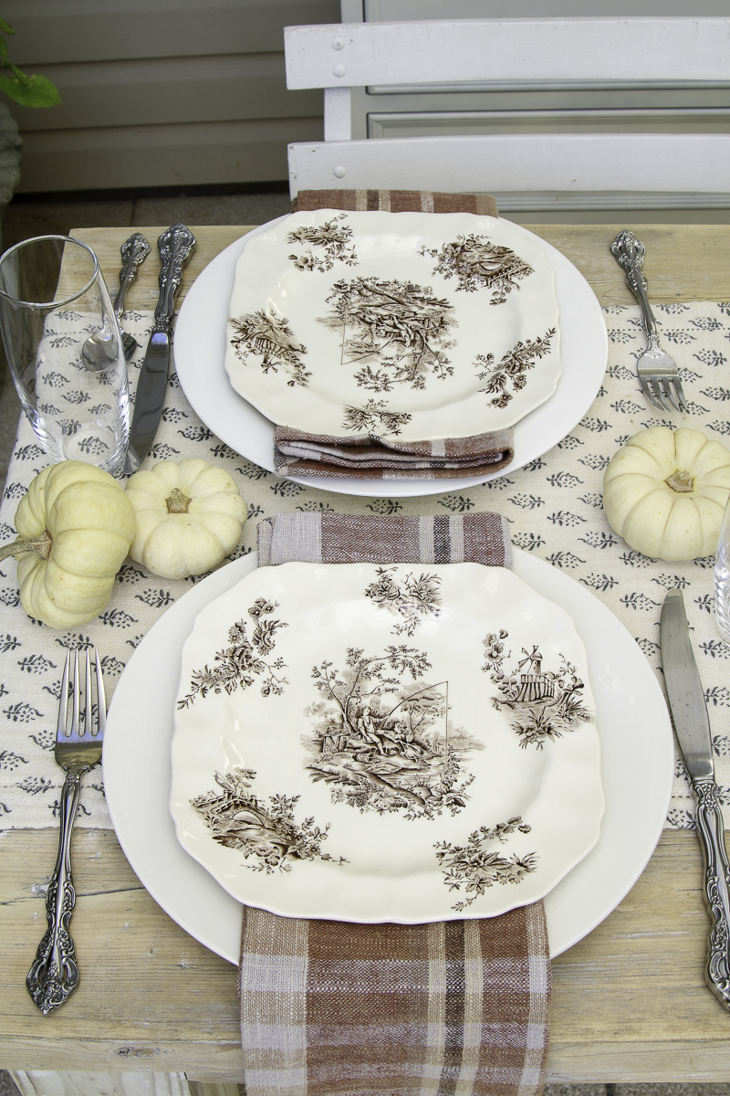Thanksgiving place setting using white Dollar Tree dishes, thrifted pattern plates in brown and white, pottery barn napkins