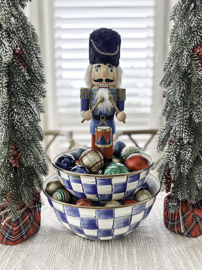 Nutcracker table centerpiece using Mackenzie Child bowls stacked with ornaments and a Nutcracker on top.