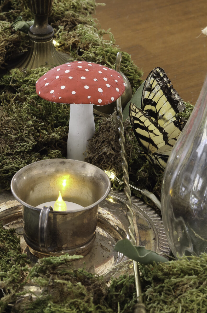 Moss table centerpiece for an whimsical enchanted garden bridal shower using vintage silver, red mushrooms, real butterflies and more.