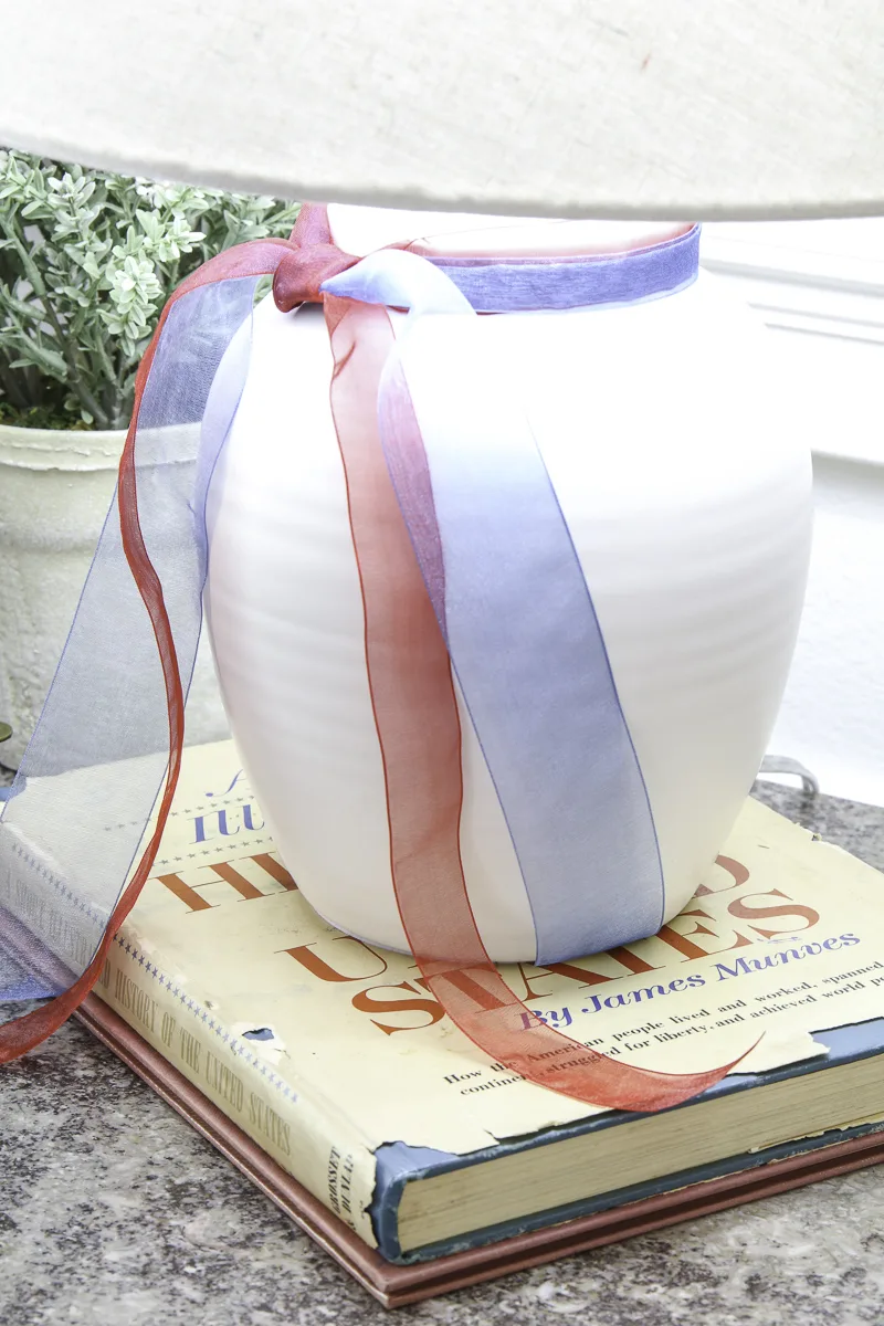 Lamb with red, white and blue ribbons and sitting on a book about American history