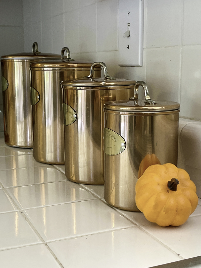 Copper canisters with an orange mini pumpkins in a kitchen