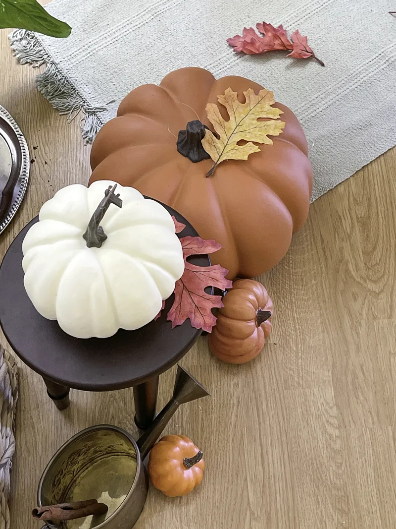 Different size pumpkins and faux leaves as decorations for fall