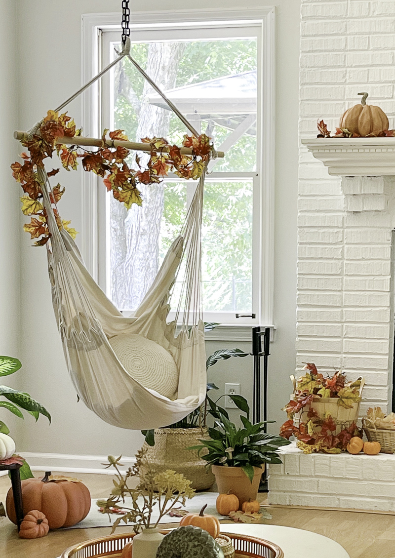 Decorating a book nook for fall with autumn leaf garland and pumpkins.