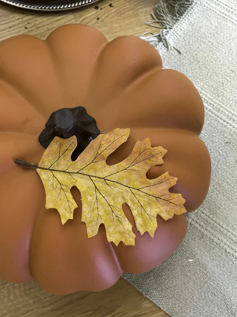 Faux leaf sitting on a pumpkin as a fall decoration