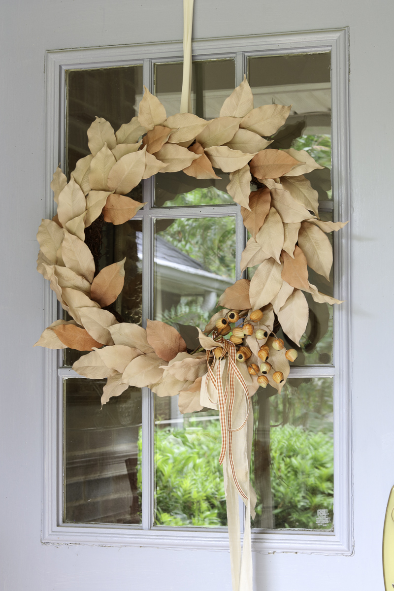 Fall front door wreath complimenting pumpkin decorations on the porch.