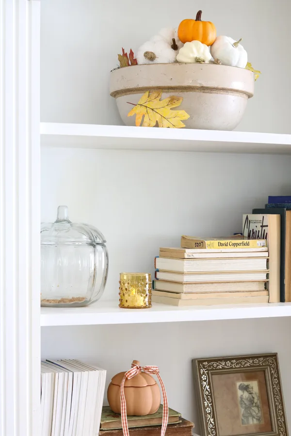 Neutral and orange fall decorations on a bookcase