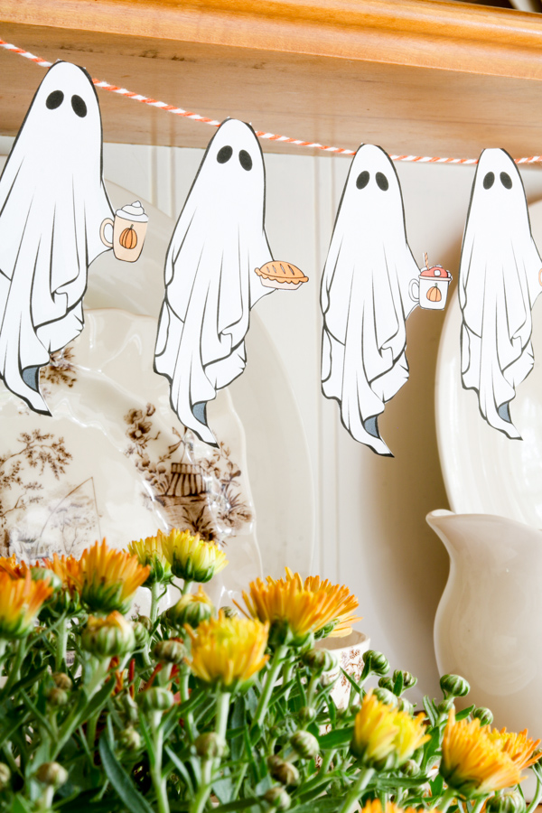 Close-up of Pumpkin Love Ghost Garland featuring paper ghosts holding pumpkin pie, pumpkin spice lattes, and pumpkins, a cute Halloween garland DIY craft.