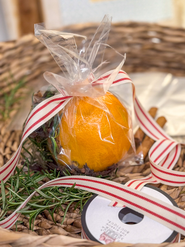 Adding a red and white ribbon to a Christmas simmer pot gift bag