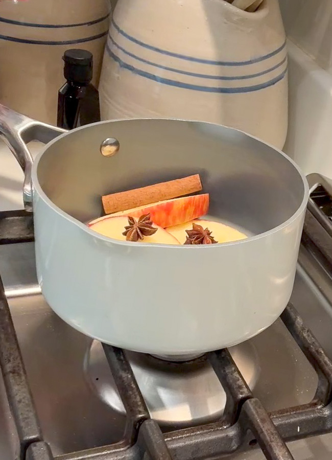 Apple pie simmer pot ingredients in a pot.  Sliced apples, cinnamon sticks, star anise and whole cloves.