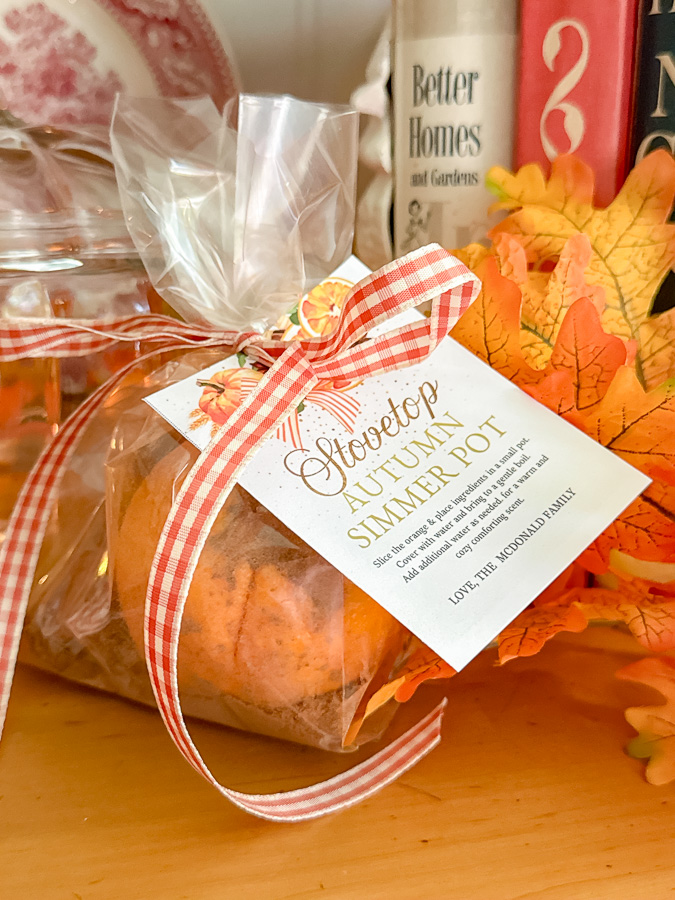 Autumn simmer pot gift of orange and spices in a clear bag with a orange and white gingham ribbon and a editable autumn gift tag