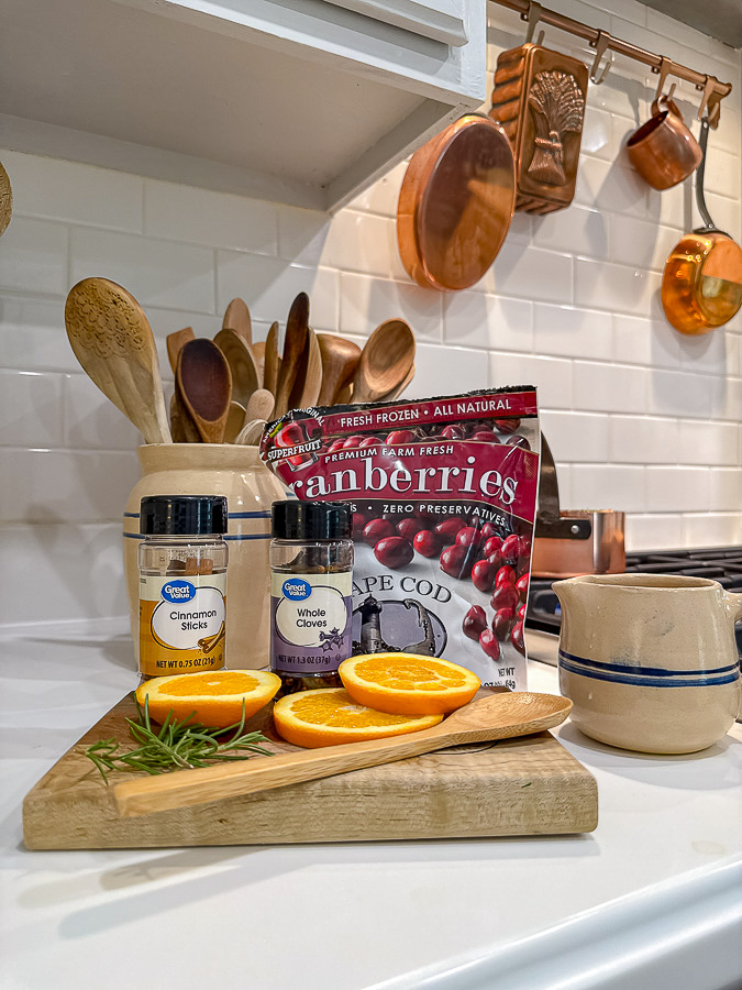 Ingredients for a cranberry orange simmer pot recipe. Cranberries, cinnamon sticks, whole clove, rosemary and orange