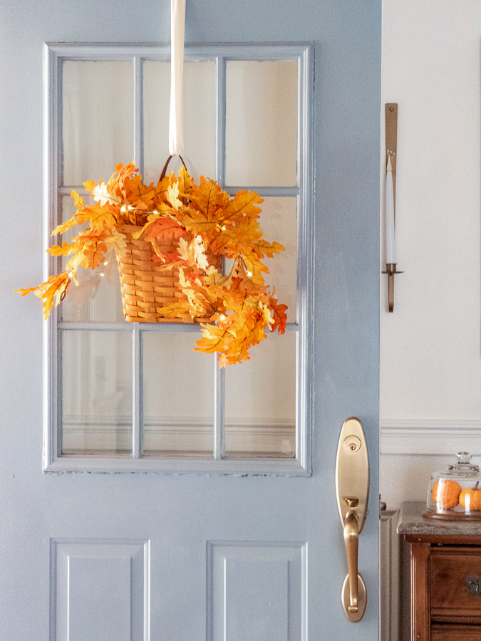 Blue door open into entryway with Longaberger hanging basket filled with autumn orange leaves