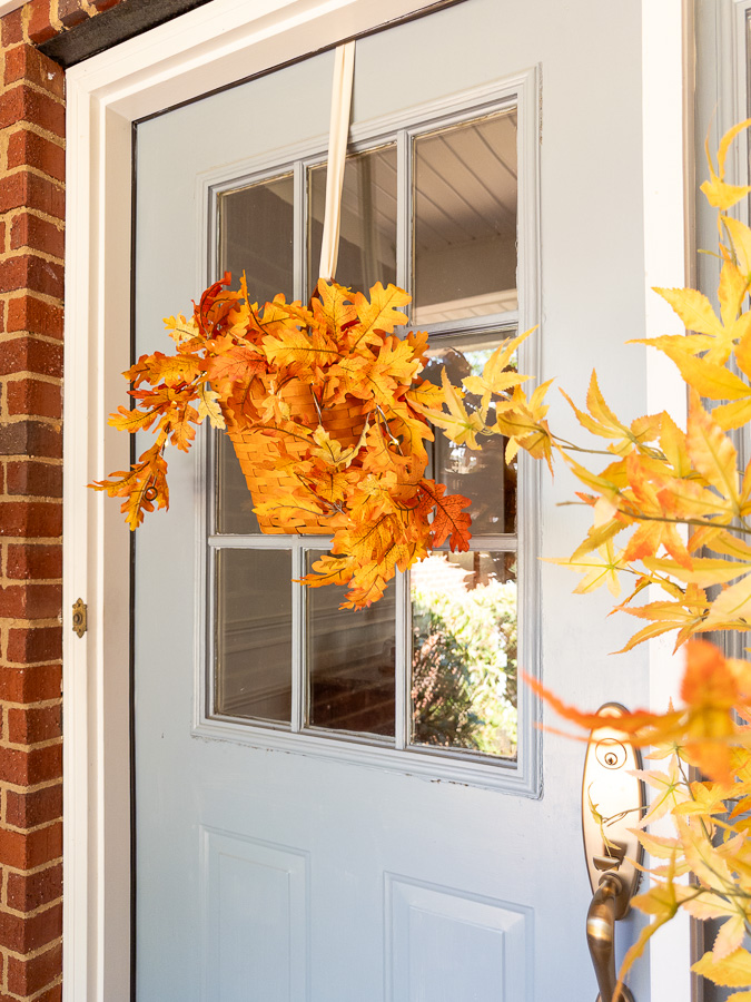 Side view of the basket hanging on the door with faux autumn leaves