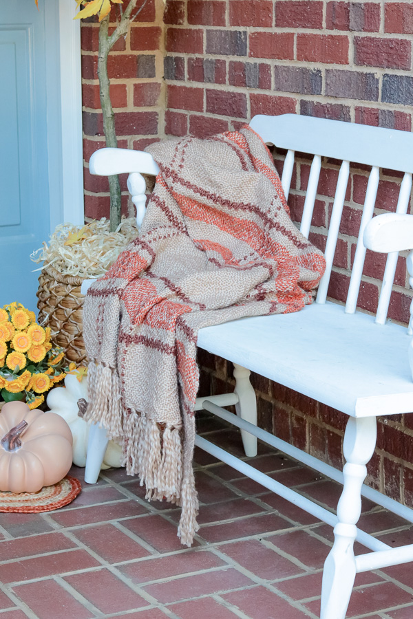 Fall blanket draped over a bench on a porch