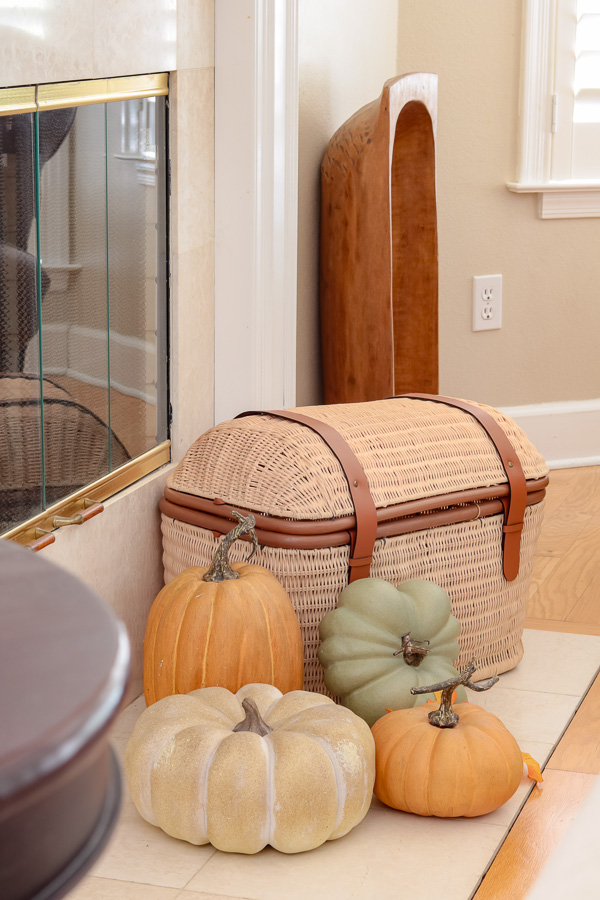Trunk shape basket on fireplace hearth with Pottery Barn faux pumpkins.