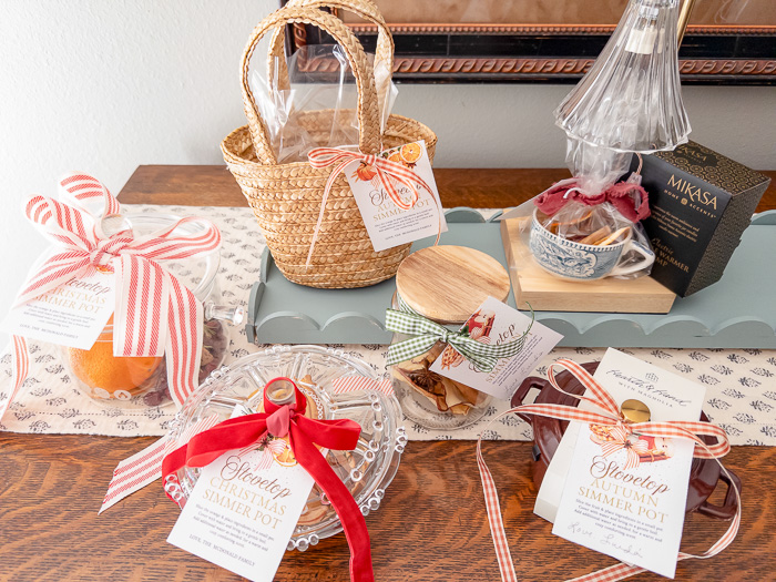 A table with simmer pot gift ideas:  glass pot, candy dish, mini market basket, mason jar, mini dutch oven and candle warmer