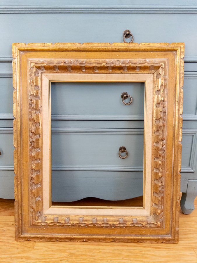 Gold vintage frame leaning against a blue dresser